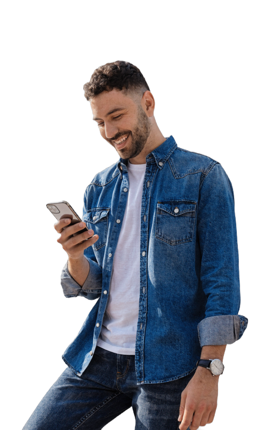 Un jeune homme en chemise denim regarde son cellulaire en souriant, au moment de voir une offre de prêt qui colle.